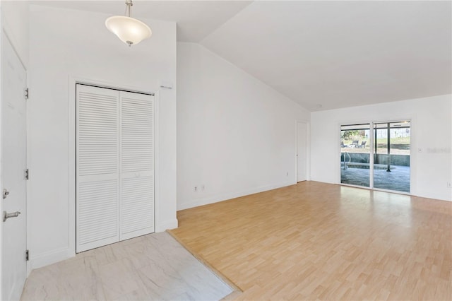 interior space with access to exterior, a closet, light hardwood / wood-style flooring, and vaulted ceiling