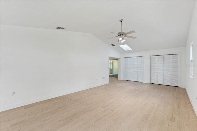 spare room with lofted ceiling with skylight, ceiling fan, and light hardwood / wood-style floors