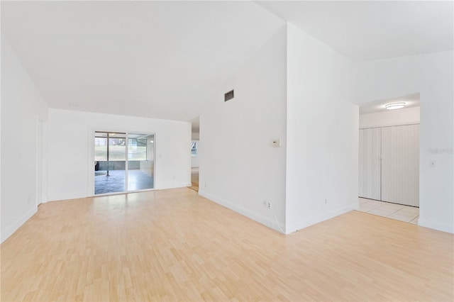 empty room with light hardwood / wood-style floors and lofted ceiling