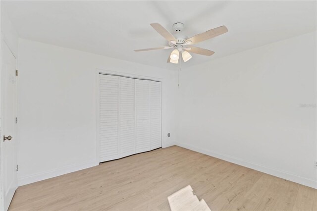 unfurnished bedroom featuring light hardwood / wood-style floors, ceiling fan, and a closet