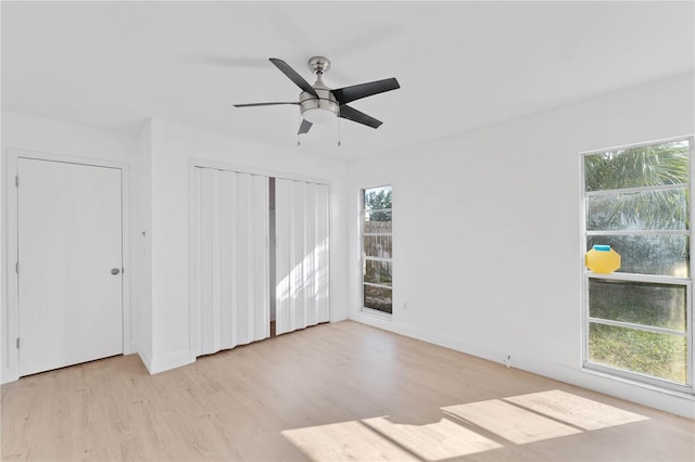 unfurnished bedroom with ceiling fan, multiple windows, and light wood-type flooring