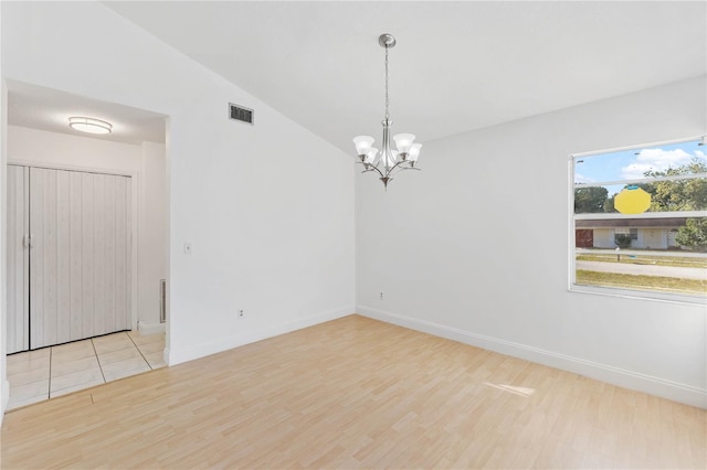 unfurnished room with a chandelier, light wood-type flooring, and lofted ceiling