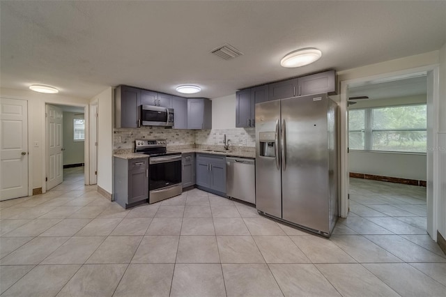 kitchen featuring decorative backsplash, appliances with stainless steel finishes, sink, and light tile patterned flooring