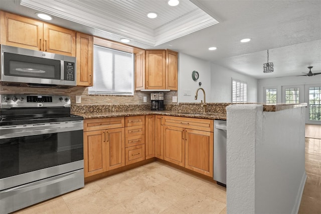 kitchen featuring decorative backsplash, appliances with stainless steel finishes, dark stone countertops, and plenty of natural light