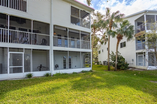 rear view of property with cooling unit, a sunroom, a yard, and a balcony