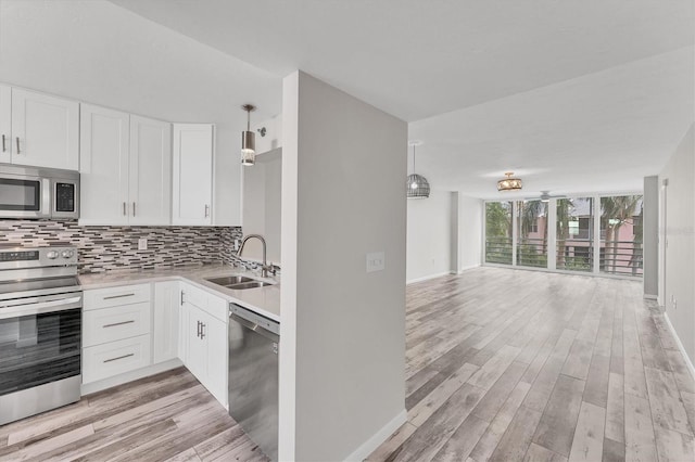 kitchen featuring white cabinetry, hanging light fixtures, sink, and stainless steel appliances