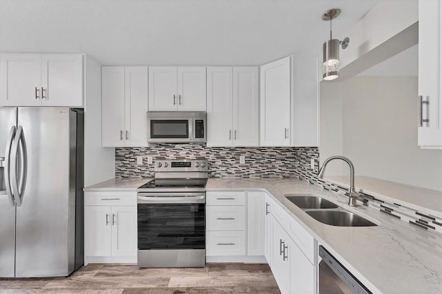 kitchen featuring appliances with stainless steel finishes, hanging light fixtures, decorative backsplash, sink, and white cabinets