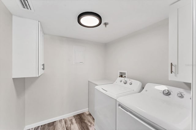 laundry area with wood-type flooring, cabinets, and washing machine and clothes dryer