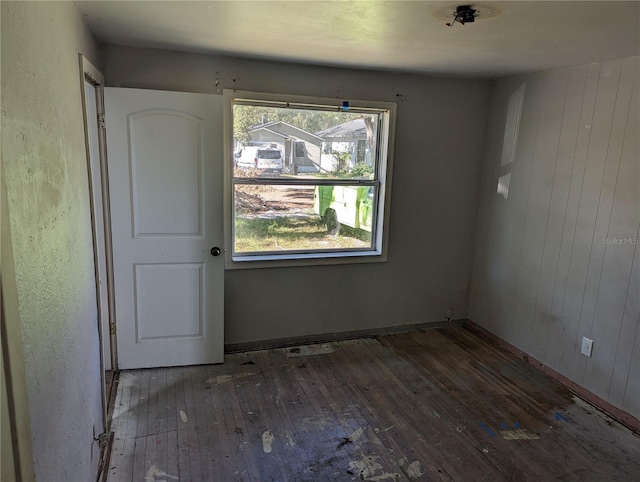 spare room featuring wood walls and dark hardwood / wood-style flooring