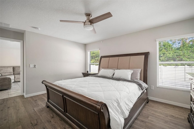 bedroom featuring a textured ceiling, wood-type flooring, and ceiling fan