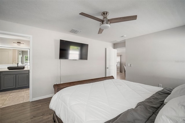 bedroom with sink, hardwood / wood-style floors, ceiling fan, and a textured ceiling