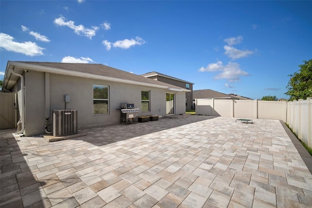 rear view of property with central AC unit and a patio