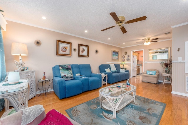 living room with ceiling fan, a textured ceiling, light hardwood / wood-style flooring, and crown molding