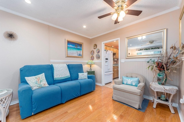 living room with ceiling fan, wood-type flooring, a textured ceiling, and crown molding