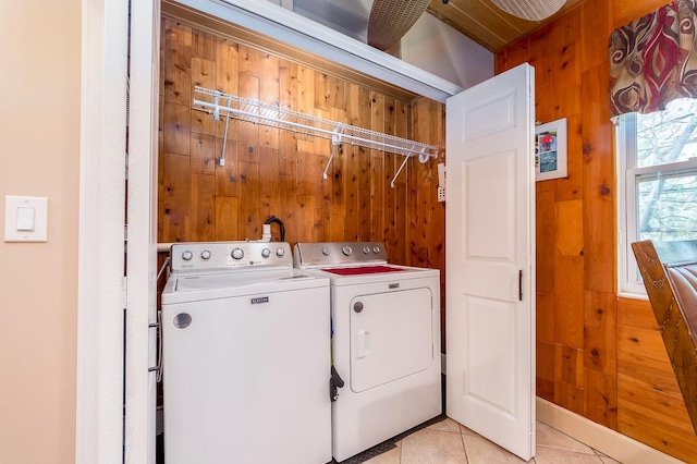 laundry area featuring wood walls, light tile patterned floors, and separate washer and dryer