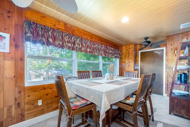 tiled dining room with wood walls, wood ceiling, ceiling fan, and plenty of natural light