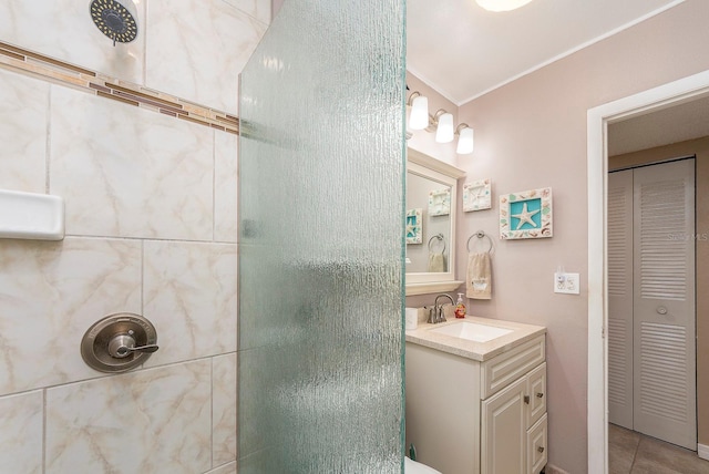 bathroom featuring tile patterned flooring, vanity, and a tile shower