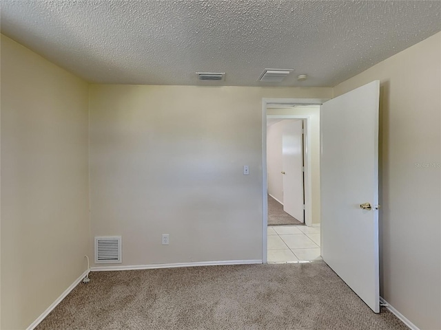 unfurnished room featuring a textured ceiling and light carpet