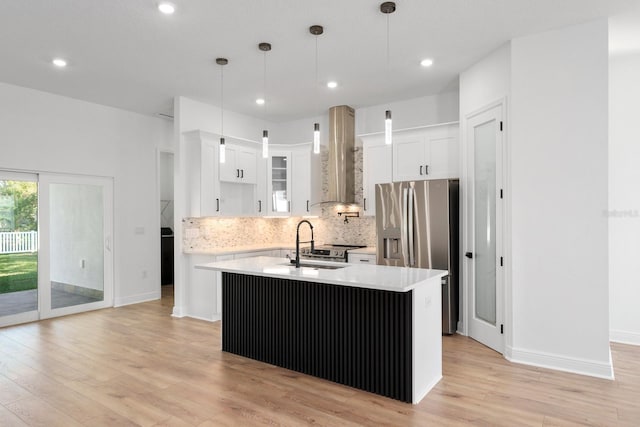 kitchen with a center island with sink, hanging light fixtures, stainless steel refrigerator with ice dispenser, sink, and white cabinetry