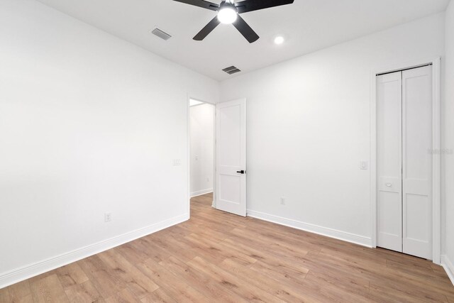 unfurnished bedroom with light wood-type flooring, ceiling fan, and a closet