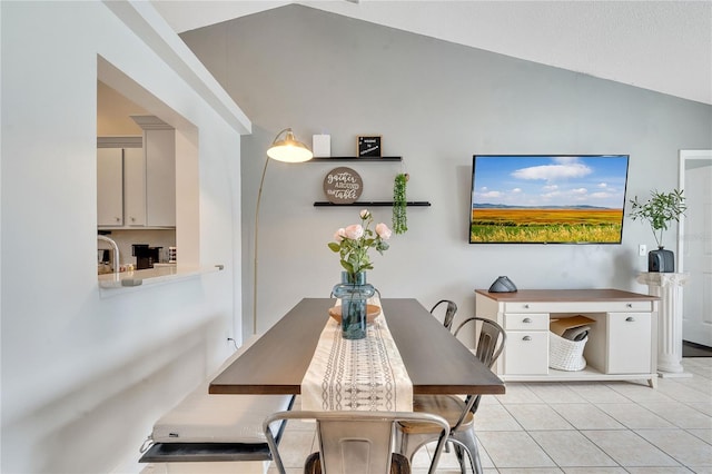 dining space with light tile patterned floors and vaulted ceiling