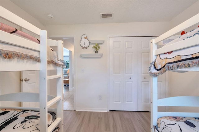 bedroom featuring a textured ceiling, a closet, and light hardwood / wood-style flooring