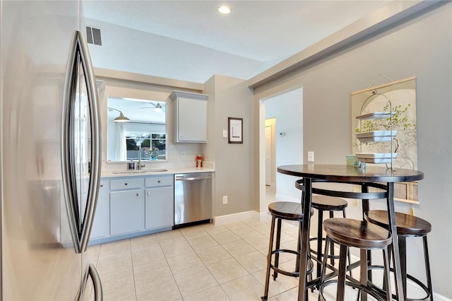 kitchen featuring appliances with stainless steel finishes, sink, a kitchen bar, and light tile patterned flooring