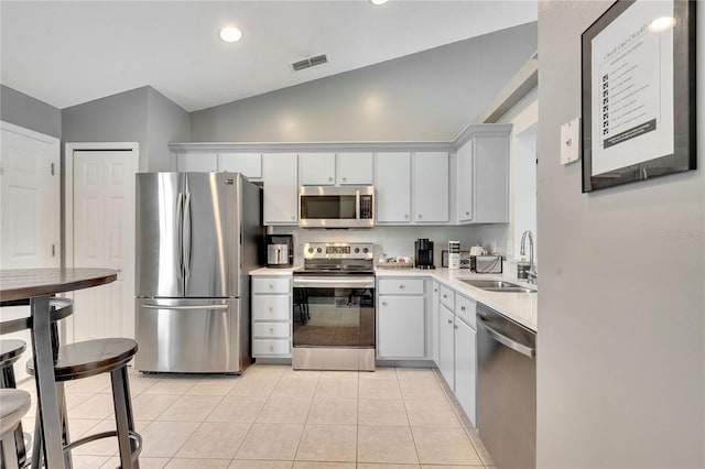 kitchen featuring light tile patterned flooring, vaulted ceiling, sink, and appliances with stainless steel finishes