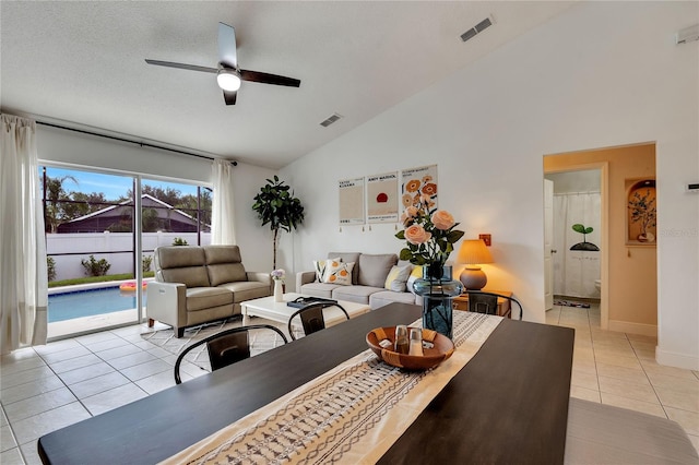 living room featuring a textured ceiling, high vaulted ceiling, light tile patterned floors, and ceiling fan