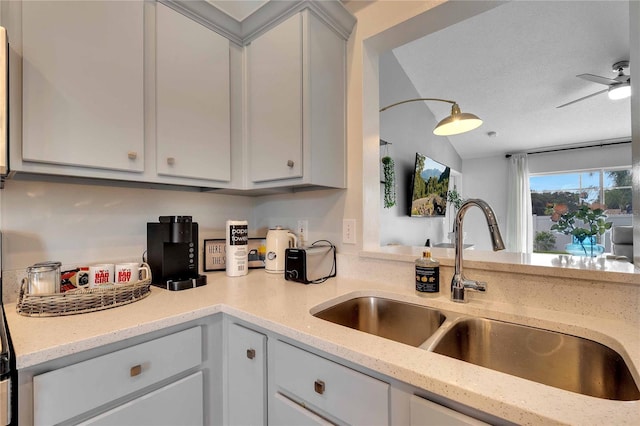 kitchen with a textured ceiling, sink, white cabinets, and light stone countertops