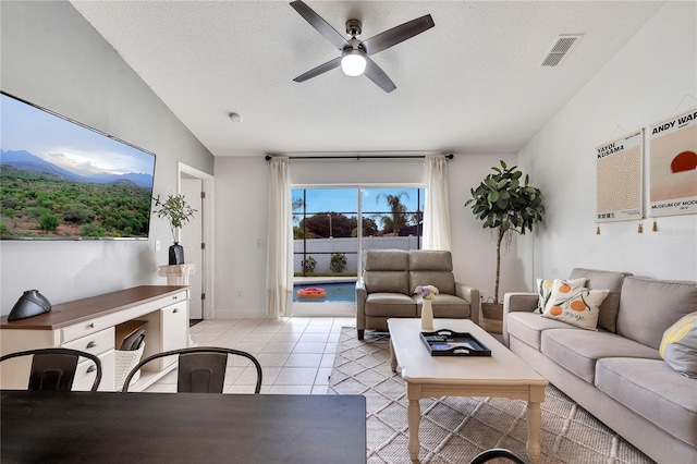 living room featuring light tile patterned flooring, lofted ceiling, a textured ceiling, and ceiling fan