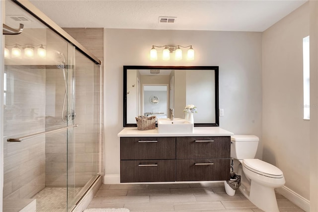 bathroom with an enclosed shower, vanity, a textured ceiling, and toilet