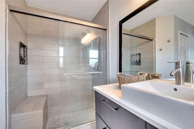 bathroom featuring walk in shower, vanity, and a textured ceiling