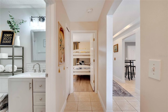 corridor featuring light tile patterned floors and sink