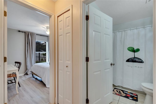 bathroom with hardwood / wood-style flooring, a textured ceiling, ceiling fan, and toilet