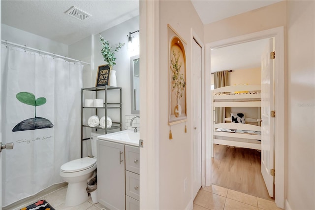 bathroom featuring toilet, vanity, a textured ceiling, and tile patterned floors