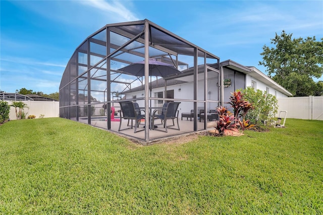 back of house with a patio, a yard, and glass enclosure