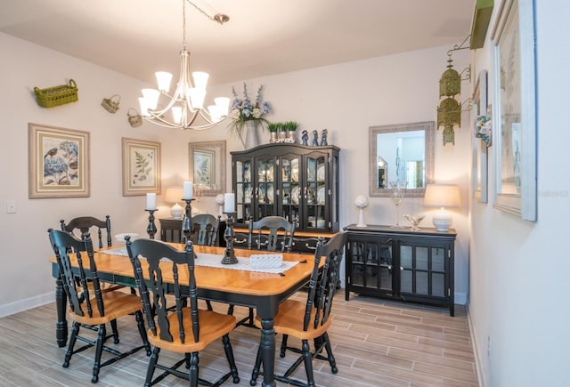 dining space with light hardwood / wood-style flooring and a chandelier