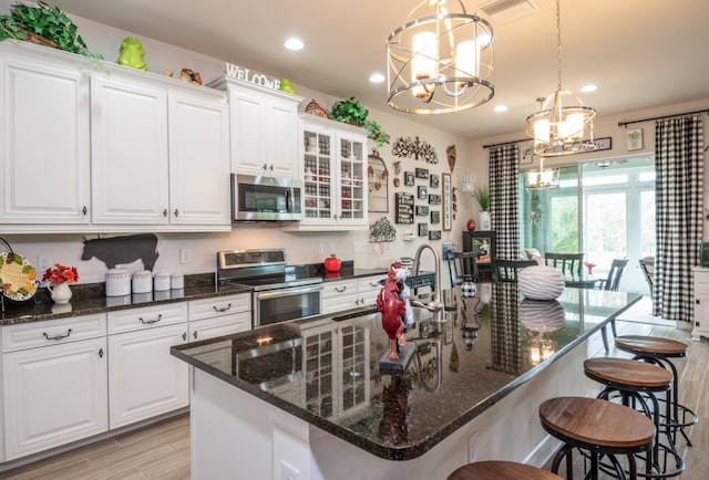 kitchen with stainless steel appliances, light hardwood / wood-style floors, white cabinetry, sink, and a breakfast bar