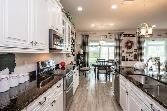 kitchen featuring stainless steel appliances, sink, an inviting chandelier, decorative light fixtures, and white cabinets