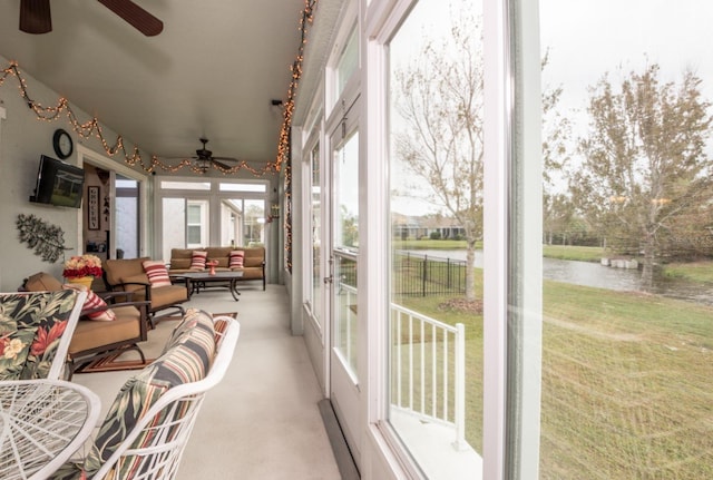 sunroom / solarium featuring ceiling fan and a water view