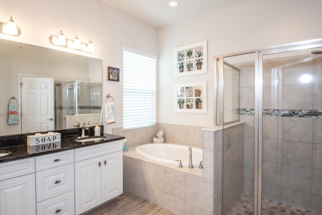 bathroom with wood-type flooring, vanity, and plus walk in shower