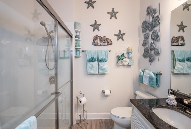 bathroom featuring hardwood / wood-style floors, a shower with door, vanity, and toilet