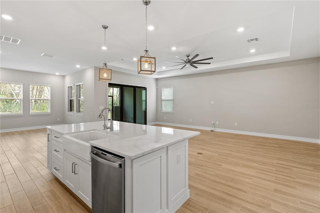 kitchen featuring a center island with sink, white cabinets, sink, stainless steel dishwasher, and light wood-type flooring