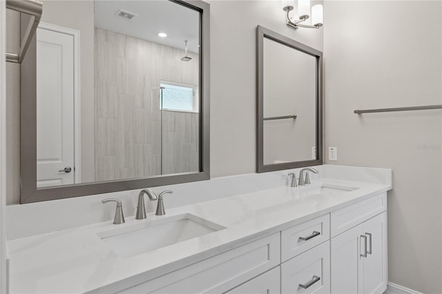 bathroom with a tile shower and vanity