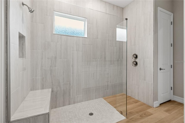 bathroom with wood-type flooring and a tile shower