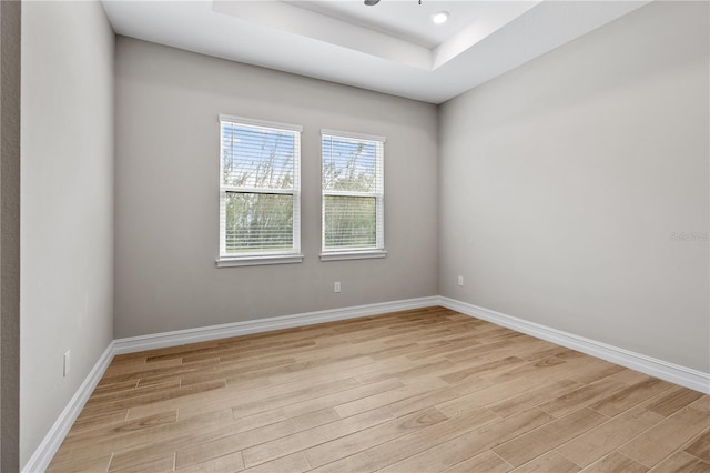 unfurnished room with light hardwood / wood-style floors and a tray ceiling