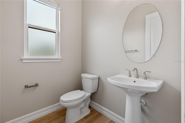 bathroom with wood-type flooring, toilet, and a wealth of natural light