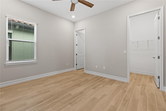 unfurnished bedroom with ceiling fan, a closet, a spacious closet, and light hardwood / wood-style flooring