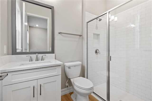 bathroom featuring wood-type flooring, vanity, toilet, and a shower with door